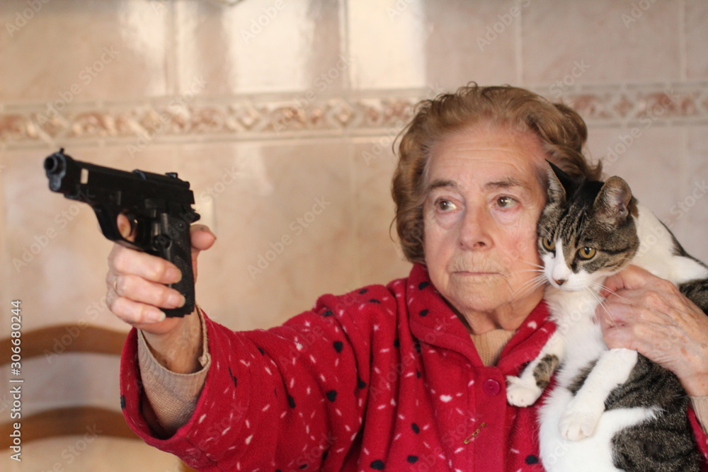 Angry senior woman protecting her cat with a gun Stock Photo | Adobe Stock