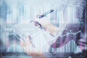 Multi exposure of hands making notes with forex chart huds. Stock market concept.