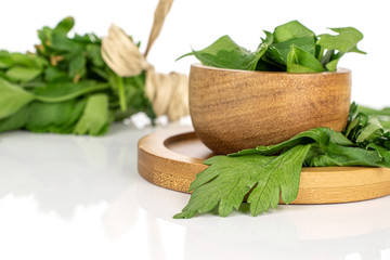 Wall Mural - Lot of whole lot of pieces of fresh green parsley front focus on round bamboo coaster in bamboo bowl isolated on white background