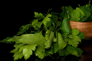 Wall Mural - Lot of whole lot of pieces of fresh green parsley in bamboo bowl isolated on black glass