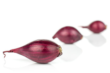 Group of three whole small red onion bulb placed diagonally isolated on white background