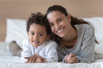 Wall Mural - Happy smiling young woman lying on bed with son.