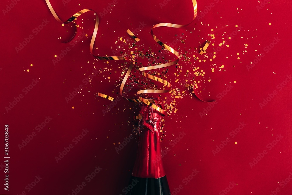 Bottle of red champagne with gold glitter, sparkles, confetti on red ...