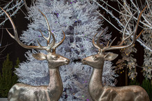 Christmas Toys - Two Figures Of Glittering Deers On The Background Of A White Christmas Tree