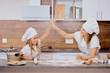 little daughter helping mother to bake, prepare dough. mom and kid dressed in aprons, clapping hands with each other