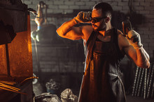 Serious Confident Forger Look At Furnace In Workshop Wearing Leather Apron And Protective Eyeglasses