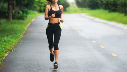 Wall Mural - Young fitness sport woman running on the road in the morning, Young fitness sportswoman runner running on tropical park trail. People and sport concept