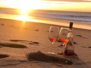 bottle of wine and two glasses on the sand