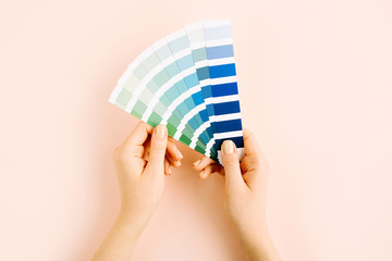 Female hand holding color swatches. Color trend palette. Flat lay, top view.