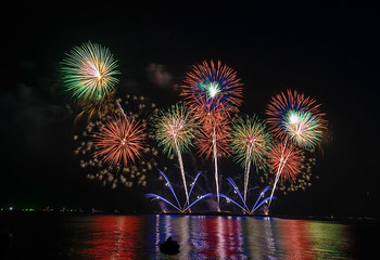 Colorful fireworks display over city on the beach. Firework celebration sparkling in midnight sky,