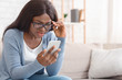 Impressed Black Girl In Eyeglasses Looking At Cellphone Screen With Disbelieve