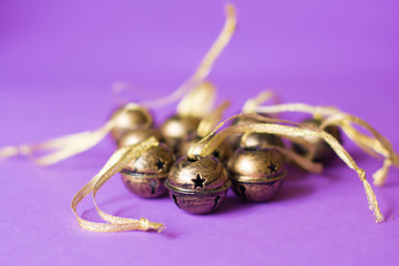 Bunch of brass sleigh bells decorations with glitter ribbons on a violet background