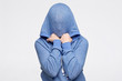Teenager hiding her face under blue sweater being frightened and stressed