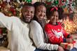 © Prostock-studio - Black parents taking selfie with their little daughter near Christmas tree
