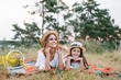 © Serhii - happy woman smiling and playing with her cute little child, lying outdoor.Loving mother and daughter spend time together in a park. Mom and kid has fun. Mother's day