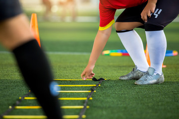 Wall Mural - Young soccer player is putting the ladder drills for soccer trainng to run and jump. Ladder drills exercises in football academy.