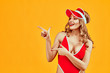 © HBS - Beautiful sexy woman dressed in red bikini advertises product against yellow background.Advertisement concept.