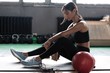 © opolja - Young woman sitting on floor after her workout and looking down. Female athlete taking rest after fitness training