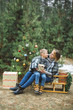 © sofiko14 - Mother and son in gray knitted sweaters enjoying beautiful winter day outdoors, while sitting on wooden sledge decorated with nice Christmas Santa presents. Decorated Christmas tree