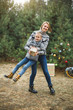 © sofiko14 - family, christmas, winter, happiness and people concept - smiling family, mom and son, in knitted sweaters, having fun standing on the background of winter forest, deocrated sledge and Christmas tree
