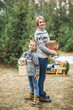 © sofiko14 - New Year and Christmas Holidays. Caucasian mom with her son holding decorated Christmas presents in arms while standing outdoors on the background of winter snowy forest.