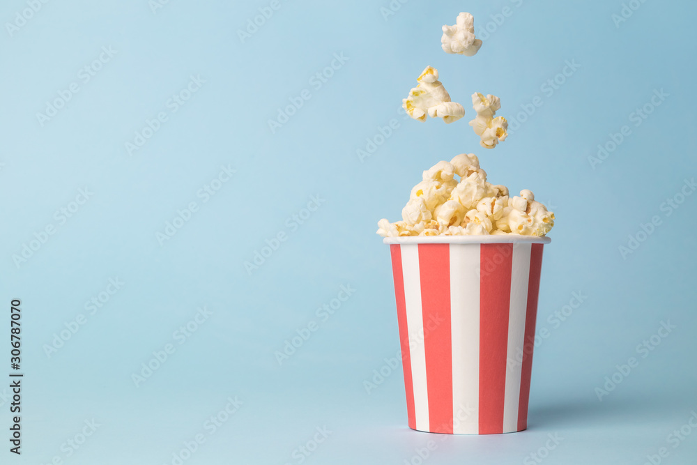 Falling popcorn in box isolated on blue. - obrazy, fototapety, plakaty 