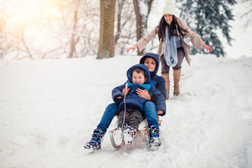 Young, beautiful mom and her cute little boy enyoing winter, sledding