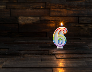 Wall Mural - Lighted birthday or anniversary candle in the form of the number six, 6, on a wooden background with copy space