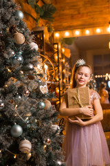 Wall Mural - beautiful girl in a dress near an elegant Christmas tree with a gift in her hands