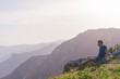 © qunica.com - Adventurous man sitting on top of a mountain and enjoying the beautiful view, while looking downhill at the blue river and amazing mountain line..