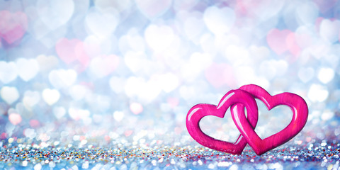 Wall Mural - two wooden interlocked hearts with colorful heart bokeh background - valentine's day/marriage concep
