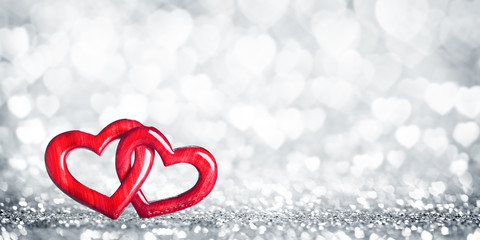Wall Mural - two wooden interlocked hearts with silver heart bokeh background - valentine's day/marriage concept