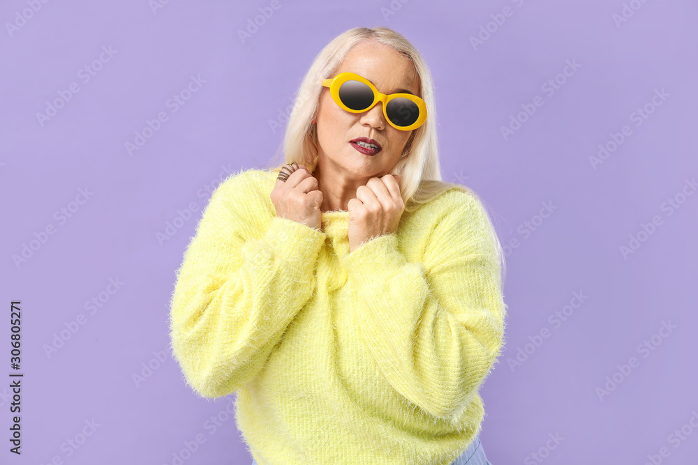 Fashionable mature woman on color background