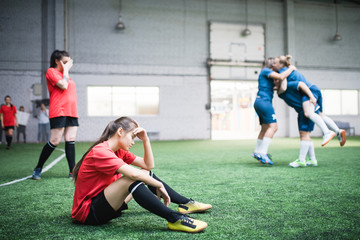 Wall Mural - Tired young female football player and other girls resting after game