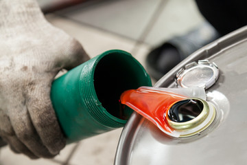 Orange chemical car wash orange flows from a canister into a green bottle. Paint for painting and building interiors and exteriors.