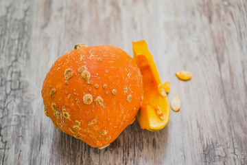 A slice of orange, yellow pumpkin and a whole pumpkin on an old wooden table. The concept of healthy eating. Vegetarian and vegan food.Vegetable diet.Still life for Halloween with copy space, space fo