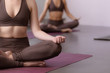 © uv_group - Close-up of young women doing yoga together. Yoga class lifestyle concept. Group of people exercising in lotus pose
