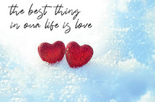 The Best Thing In Our Life Is Love - Inspiration Quote. Two Red Hearts On Snow Background. Heart, Symbol Of Love, February 14, Valentine's Day. Shallow Depth, Close Up