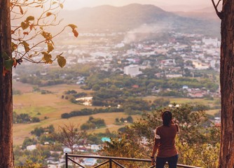 Wall Mural - Traveler woman standing on the top of mountain in beautiful nature at North Thailand forest and city.Beautiful landscape for adventure travel.