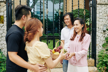 Poster - Happy mature Asian couple greeting adult son and his girlfriend at entrance gates