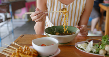 Sticker - Woman eat boat noodles at outdoor street vendor in Thailand