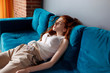 © Dmitrii Kotin - Young redhead woman reclining on the couch and feels tired.