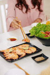 Poster - Close-up image of woman taking shrimp with chopsticks from plate when eating dinner at home