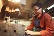 © Seventyfour - Side view portrait of smiling woman operating industrial machine units at metalworking plant, copy space