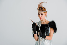 Attractive Woman Touching Retro Microphone And Holding Cigarette Holder Isolated On Grey