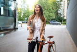 Fototapeta  - Business woman with bicycle to work on urban street in city. Transport and healthy lifestyle concept