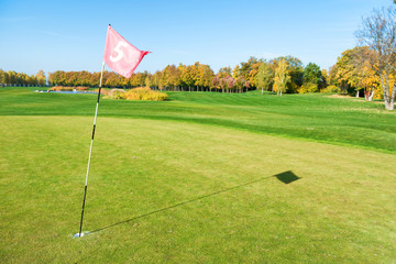 Golf flag near trap on green golf field