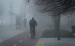 Cyclist in the city is moving along a bicycle path in fog