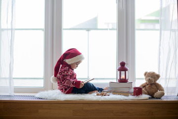 Sticker - Sweet blonde child, boy, sitting on window shield with teddy bear friend toy, writing letter to Santa Claus and reading book