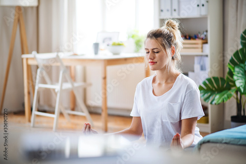 Fotomural Young woman doing yoga exercise indoors at home, meditating.